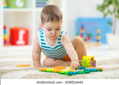 toddler boy playing indoors with educational toy sitting on soft carpet