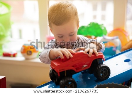 Toddler boy plays with car toys in the children's room. Educational toys for young children. Child one and a half years - two years. Selective focus