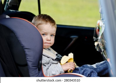  Toddler Boy Sitting In The Car Seat And Eating A Banana