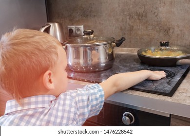 Toddler Boy Touches Hot Stove In Kitchen. Accident At Home With Children. Child Pulls A Hand To A Scorching Pan