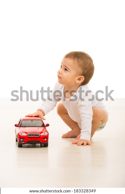 Toddler boy with\
toy car looking away in\
home