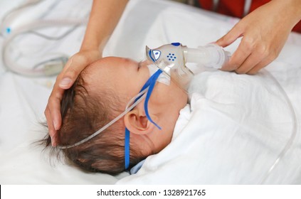 Toddler boy using nebulizer to cure asthma or pneumonia disease . Sick baby boy rest on patients bed and has inhalation therapy by the mask of inhaler. Respiratory Syncytial Virus (RSV).