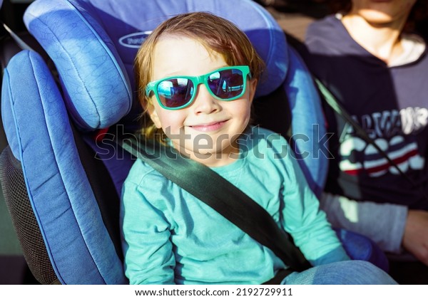 Toddler boy weraing sun\
glasses sitting in a car seat, family travelling by car. Preschool\
child in the auto.