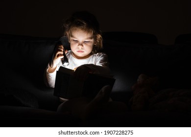 Toddler Caucasian Girl Reading Book At Hight With Flashlight. Unplugged Childhood Activities. Goodnight Bedtime Routine. Reading Fantasy Farytale