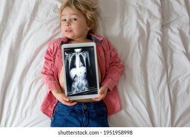 Toddler Child, Blond Boy, Holding X-ray Picture On Tablet Of Child Body With Swallowed Magnet Showing, Child Swallow Dangerous Object