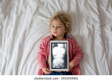 Toddler Child, Blond Boy, Holding X-ray Picture On Tablet Of Child Body With Swallowed Magnet Showing, Child Swallow Dangerous Object