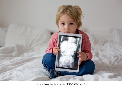 Toddler Child, Blond Boy, Holding X-ray Picture On Tablet Of Child Body With Swallowed Magnet Showing, Child Swallow Dangerous Object