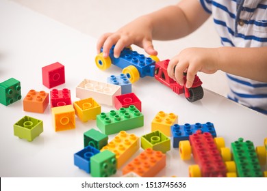 Toddler Child Playing Multi-colored Cubes On The Table. Colorful Plastic Bricks For The Early Development Of The Child. Early Learning And Educational Toys For A Little Boy