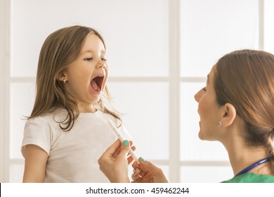 Toddler Child Take An Oral Medical Suspension With Syringe. Young Female Doctor Giving Little Girl Medicine