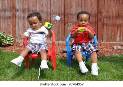 Toddler Children Sitting Playing Outside On Lush Green Lawn