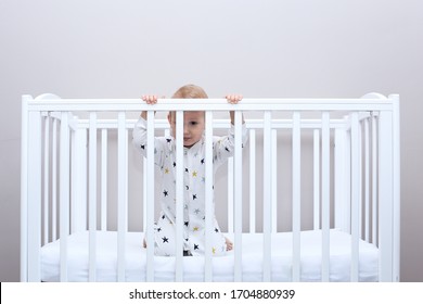 toddler is in the crib. baby is looking through bars of crib. kids home quarantine