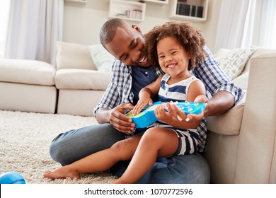 Toddler Daughter Sits On DadÕs Knee Playing Ukulele At Home