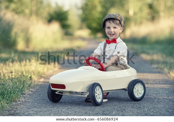 Toddler driving\
a retro car, funny boy in toy\
car