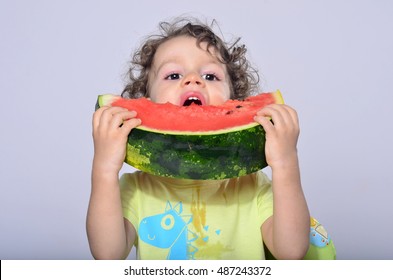 Toddler Eating A Slice Of A Sweet Delicious Watermelon. Hungry Kid Biting From A Piece Of Melon And Getting Messy