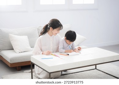 A toddler enjoys learning while opening a notebook under Mom's watchful eye Enjoying activities like drawing and coloring together,wide angle