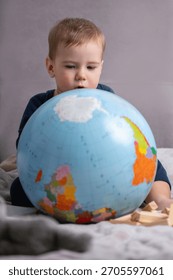 Toddler exploring a globe while imagining future travels
