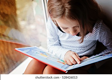 toddler girl with book near the window - Shutterstock ID 528426013