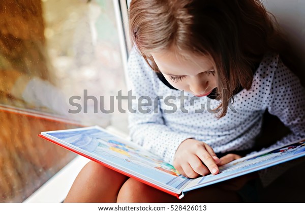 窓際に本を持つ幼い女の子 の写真素材 今すぐ編集