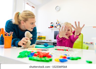 Toddler girl in child occupational therapy session doing sensory playful exercises with her therapist. 