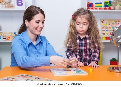 Toddler Girl In Child Occupational Therapy Session Doing Sensory Playful Exercises With Her Therapist.