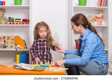 Toddler Girl In Child Occupational Therapy Session Doing Sensory Playful Exercises With Her Therapist.