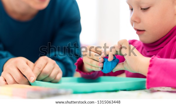 Toddler girl in child\
occupational therapy session doing sensory playful exercises with\
her therapist. 