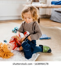 Toddler girl dressing doll in living room - Hindeloopen, Friesland, Netherlands