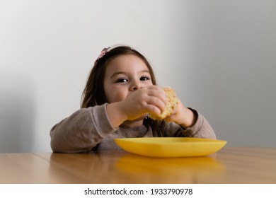 Toddler Girl Eating Bread Or Pie At Home With Her Hands. Hungry Kid. Unhealthy Diet. Bad Table Manners