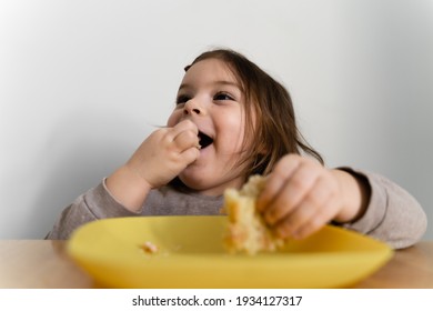 Toddler Girl Eating Bread Or Pie At Home With Her Hands. Hungry Kid. Unhealthy Diet. Bad Table Manners