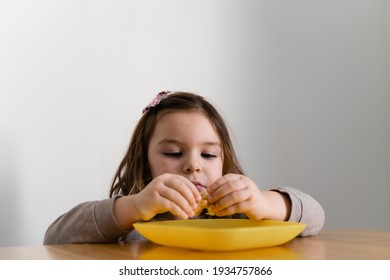 Toddler Girl Eating Bread Or Pie At Home With Her Hands. Hungry Kid. Unhealthy Diet. Bad Table Manners