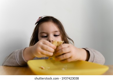 Toddler Girl Eating Bread Or Pie At Home With Her Hands. Hungry Kid. Unhealthy Diet. Bad Table Manners