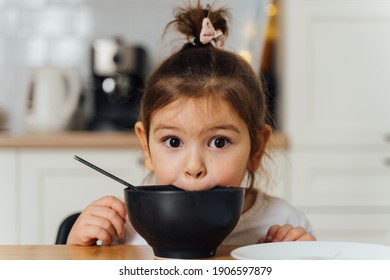 Toddler Girl Picky Eater At Home Kitchen. Learning O Eat With Spoon. Bad Table Manners Of Kid