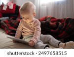 Toddler girl playing with digital wireless tablet computer on couch at home. 