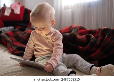 Toddler girl playing with digital wireless tablet computer on couch at home.  - Powered by Shutterstock