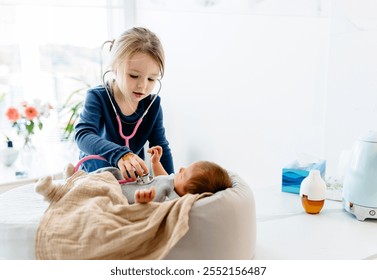 Toddler girl playing doctor with newborn baby lying on cocoon in nest for newborns. She engaged with stethoscope, bringing warmth and fun to family playtime. Bright, airy room, sister and brother. - Powered by Shutterstock