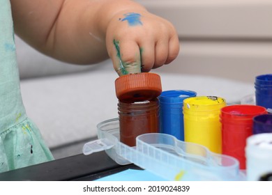 Toddler girl playing outside painting and exploring sensory, exploring color and exploring process and outcome - Shutterstock ID 2019024839