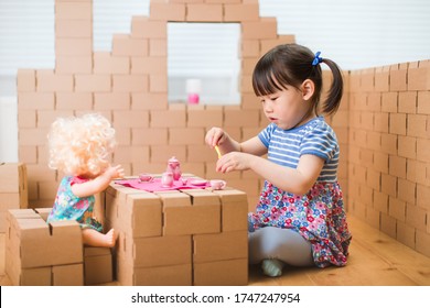 toddler girl pretend play baby care in a cardboard block house