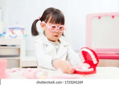 Toddler Girl Pretend Play Dentist Role At Home Against White Background