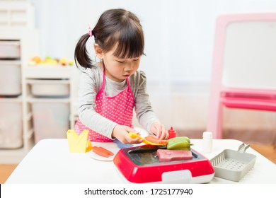 Toddler Girl Pretend Play Food Preparing Role At Home Against White Background