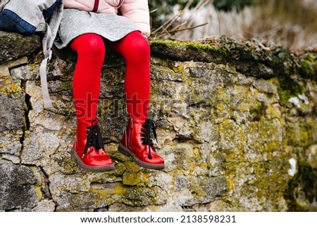 Toddler girl in red shoes and pantihose stockings. Child with backpack to nursery or playschool. Stylish and beautiful clothes and shoes for kids.