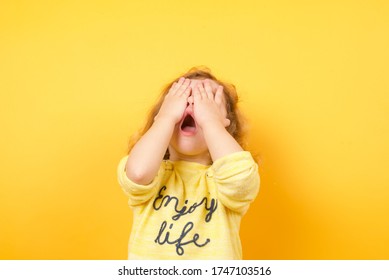 Toddler Girl Scared Or Crying Girl Hiding Face Standing Over Yellow Background 
