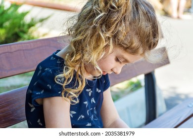 Toddler Girl Sitting Hunched Over on a Bench .Bad Body Posture 