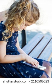 Toddler Girl Sitting Hunched Over on a Bench and looking her mobile phone .Bad Body Posture 
