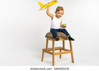 Toddler Girl Sitting On And Posing With A Yellow Plane Toy. Gender Stereotypes.