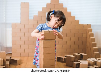 Toddler Girl Use Cardboard  Blocks To Build House At Home 