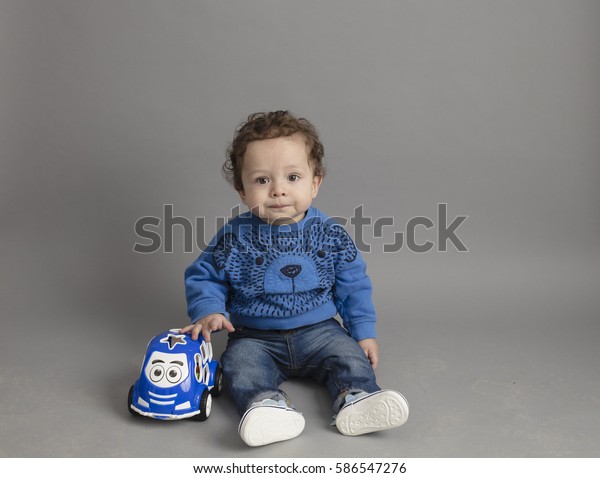 toddler\
with his small car toy isolated inside\
studio