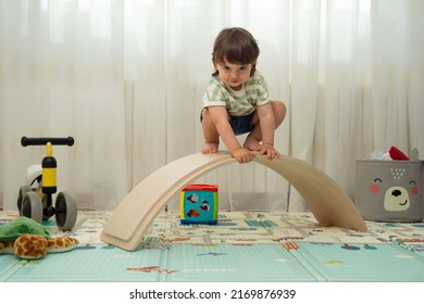 Toddler Looking At The Camera On A Balance Board In A Montessori Playroom.