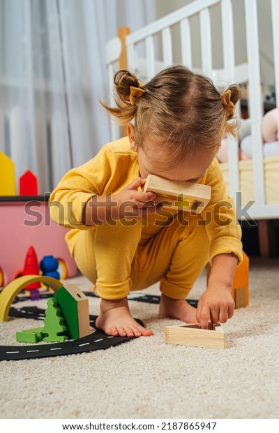 Toddler  looking through the colorful window of a toy.
Educational game for baby  in modern nursery. A little girl looking
through transparent colored block toy. Wooden rainbow stacking
blocks. 