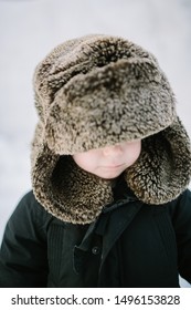 Toddler In Oversized Fur Trapper Hat In The Snow