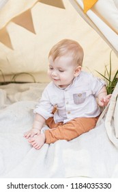 Toddler Playing In Cotton Teepee With Window, Decorated With Flags. One Year Cute Boy In A Teepee Outdoors.